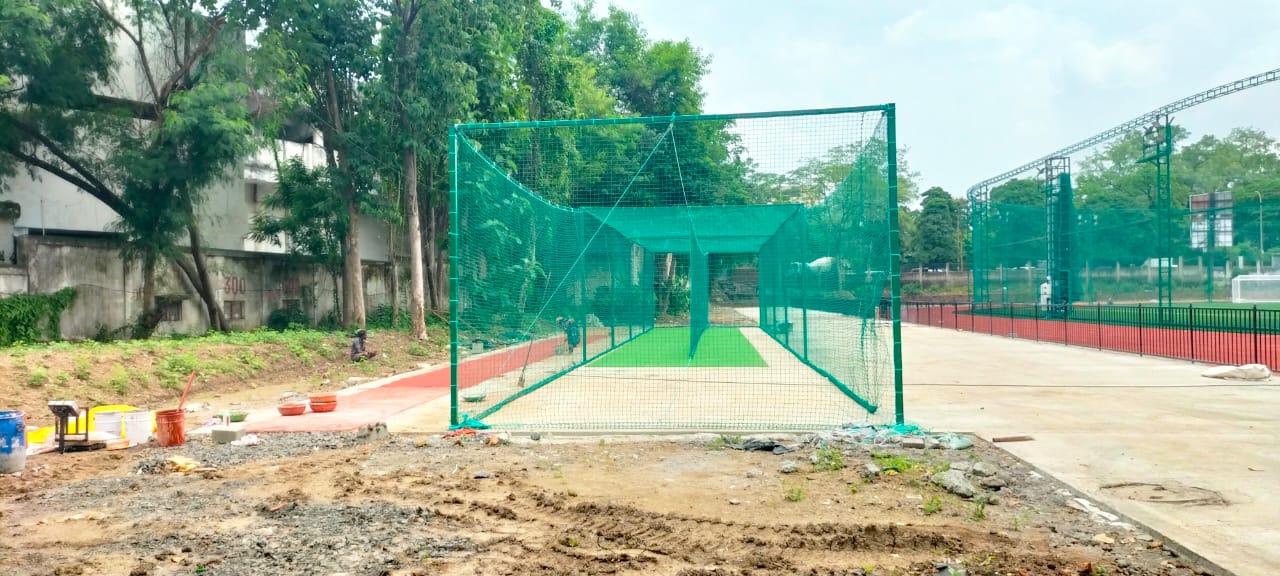 Green cricket practice net enclosure with artificial grass pitch